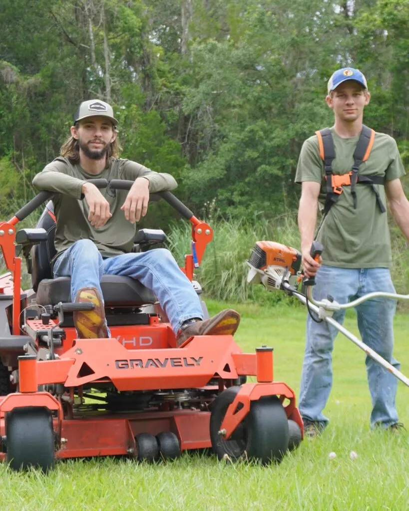 Two Tons Agricultural Services crew members posing with mowing and trimming equipment.