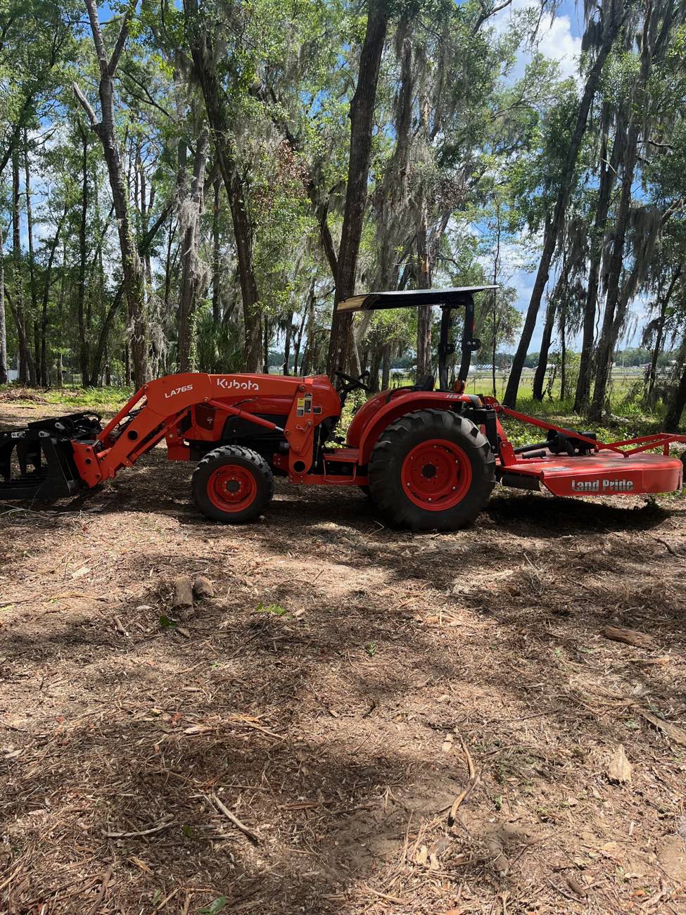Kubota tractor with brush mower clearing a lakeside lot